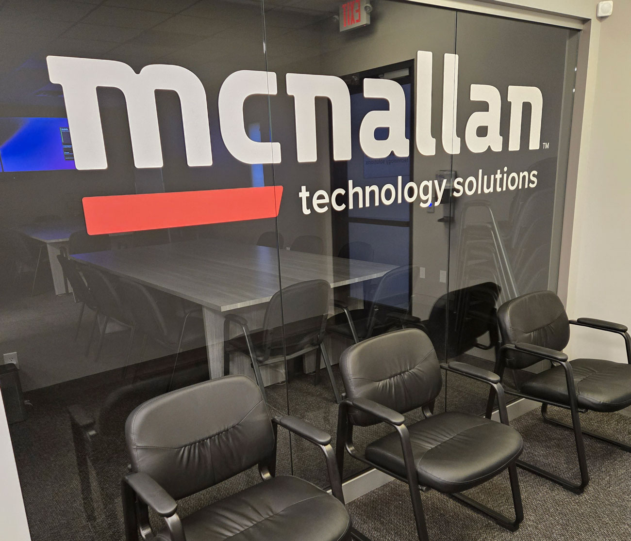 The McNallan Technology Solutions logo on the glass conference-room wall at the Brooklyn Park office
